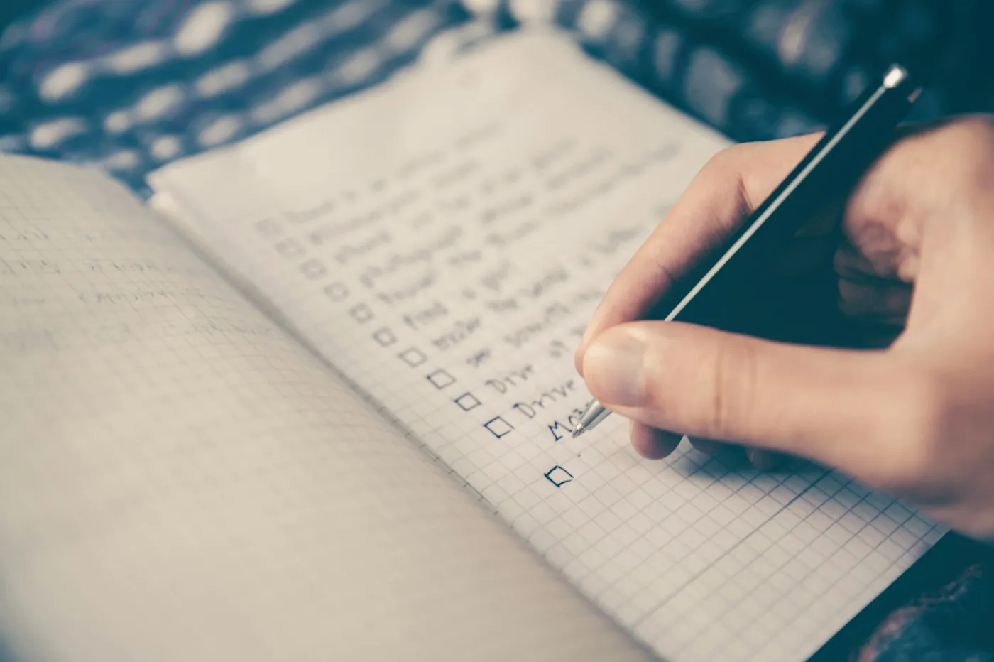 Hand ticking off a checklist in a notebook while planning the week