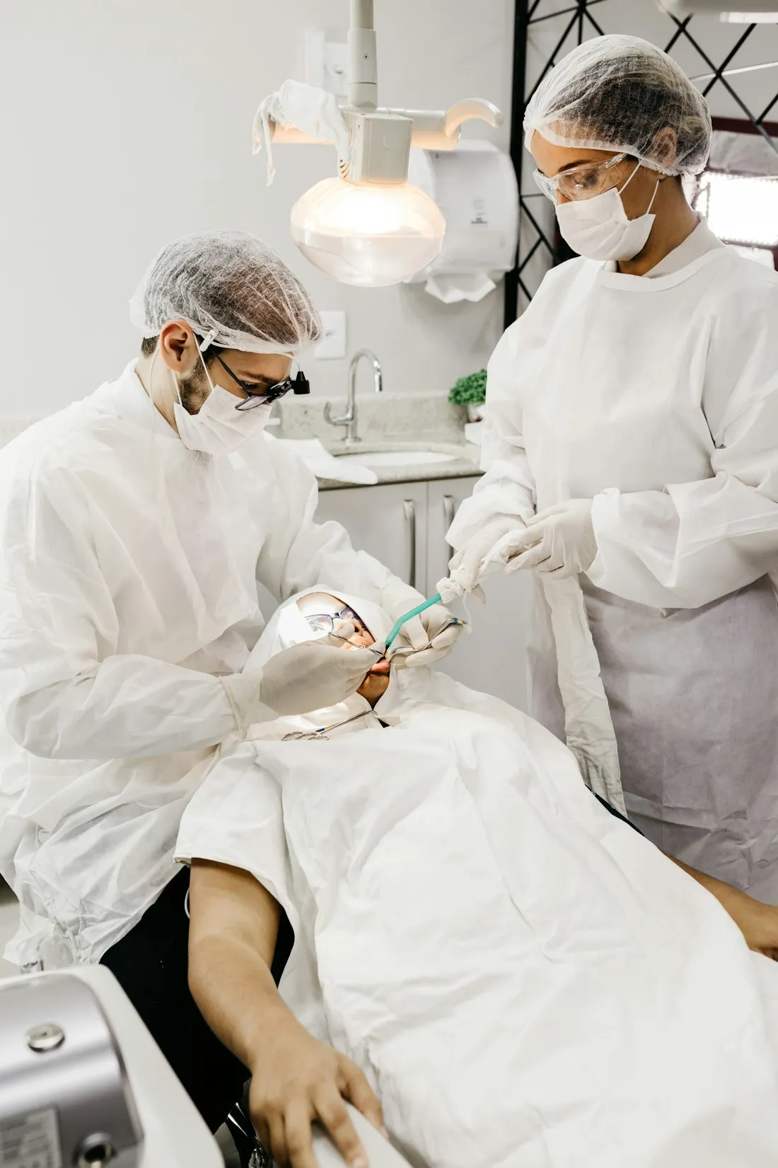 Two clinicians in full personal protective equipment working together while treating a patient