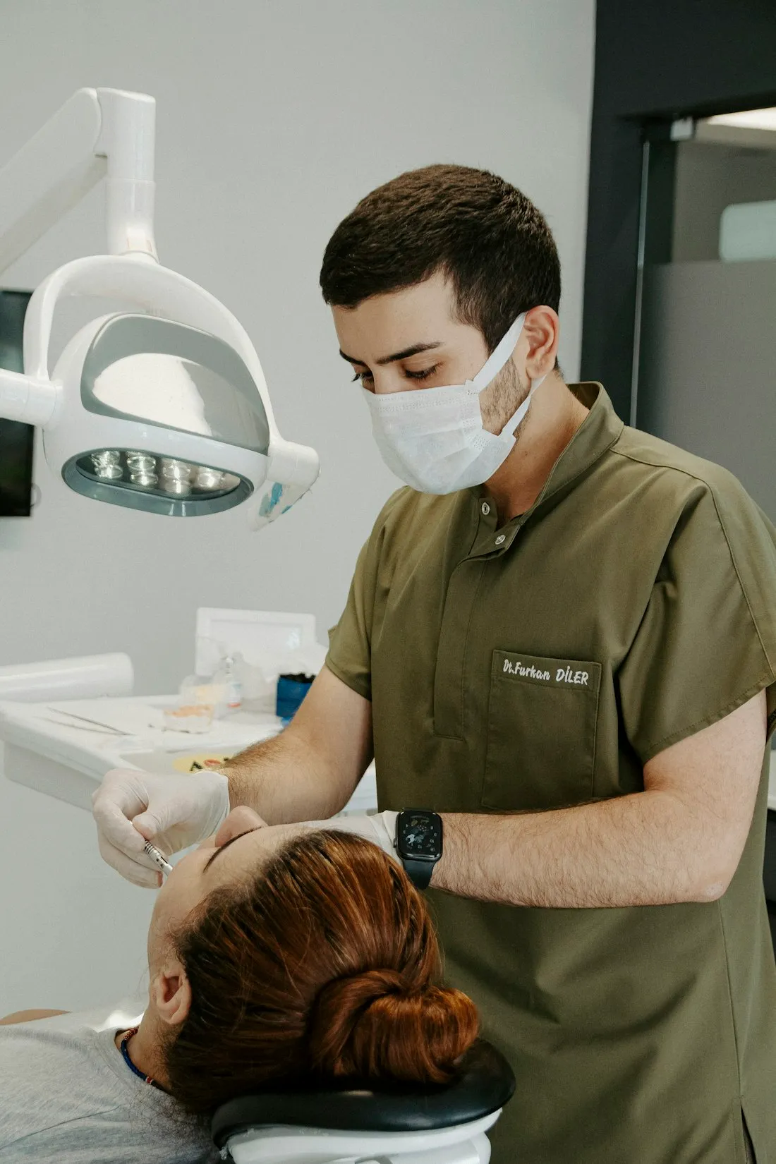 Dentist in scrubs working on a patient under the treatment light