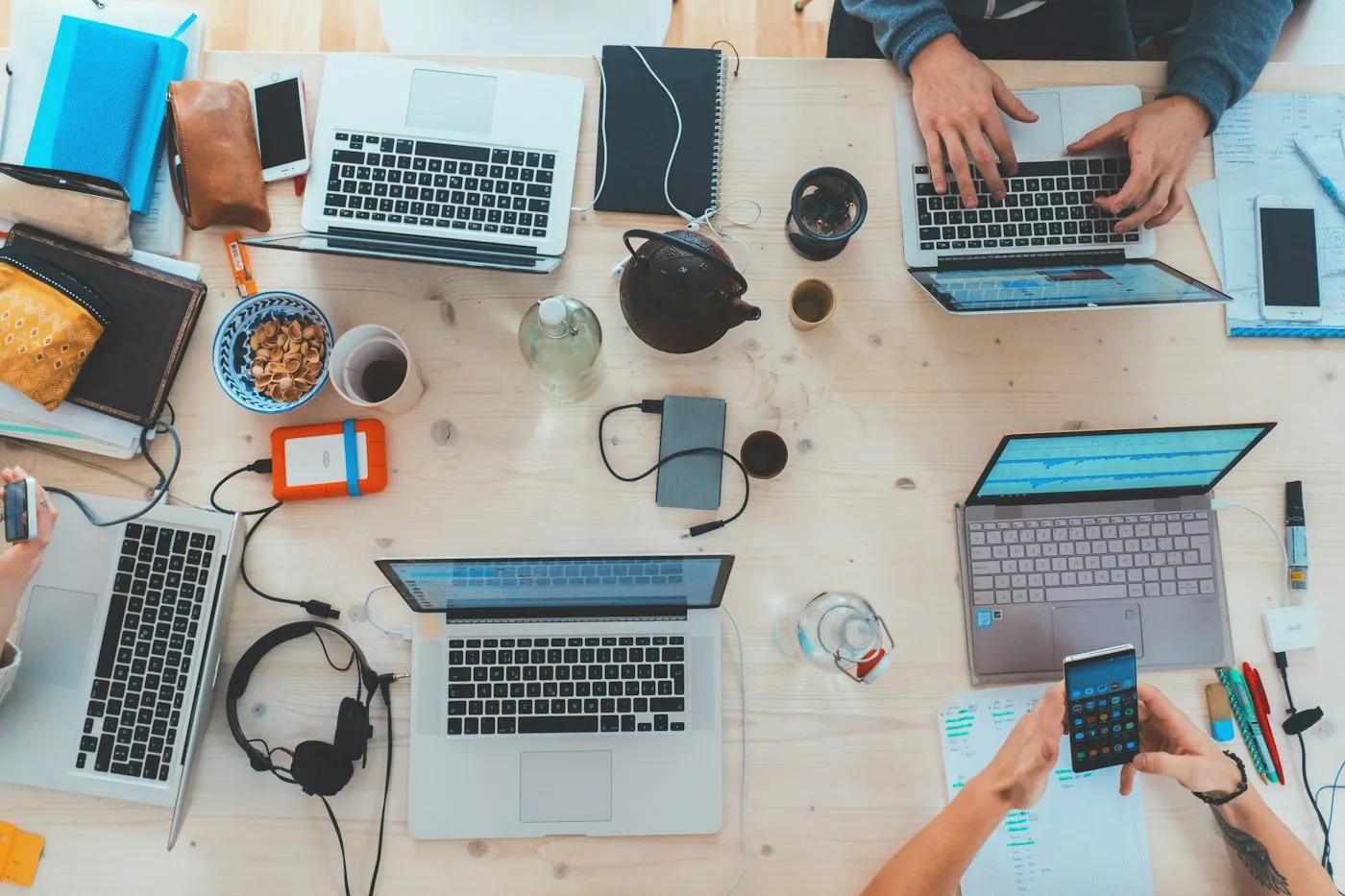 Overhead view of a team working together on laptops and notebooks around a shared desk